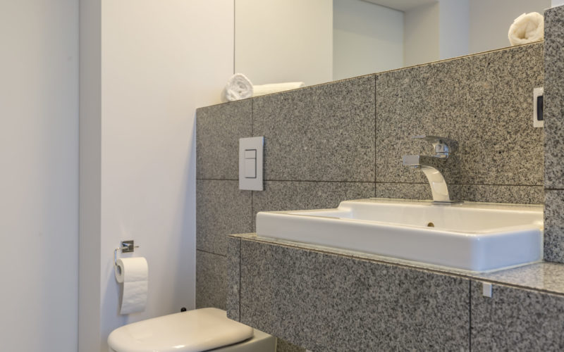 Granite tiles in modern minimalist bathroom with toilet and washbasin